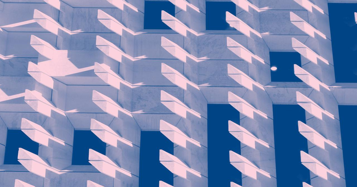 Abstract geometric building facade with deep angular shadows and repeating rectangular forms in neutral tones